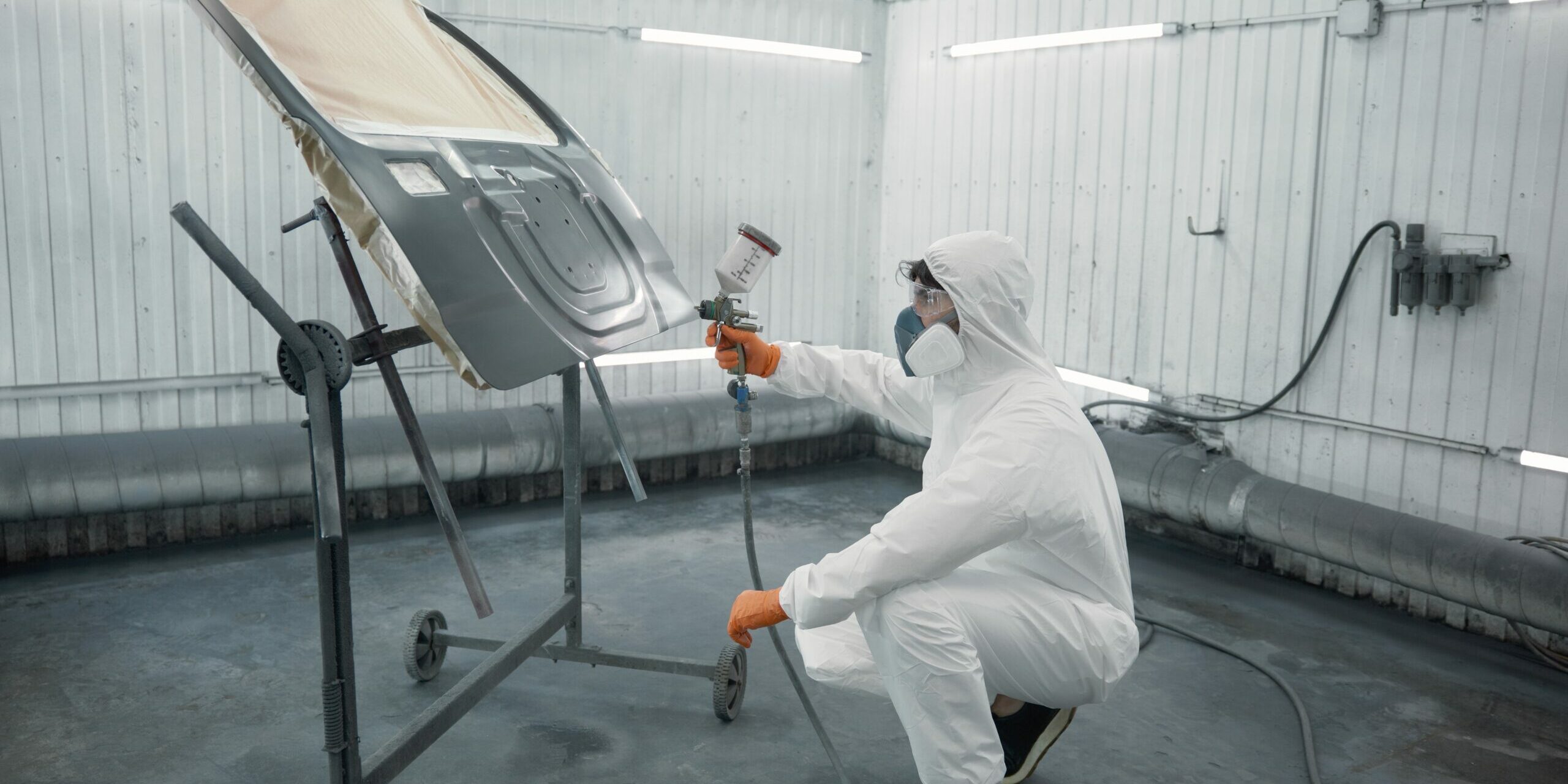 A,Technician,Spray-painting,Car,Hood,Inside,A,Controlled,Automotive,Spray A technician spray-painting the bonnet of a car inside a booth.